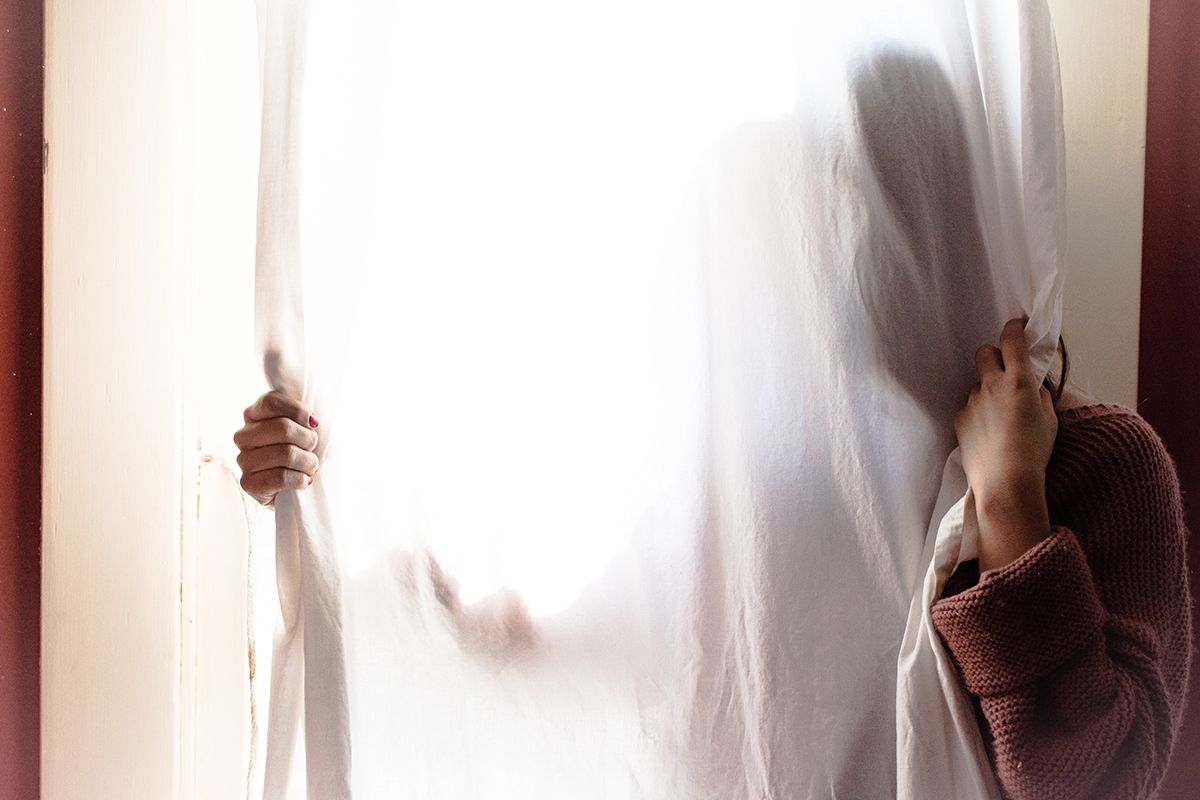 Woman behind translucent white curtain