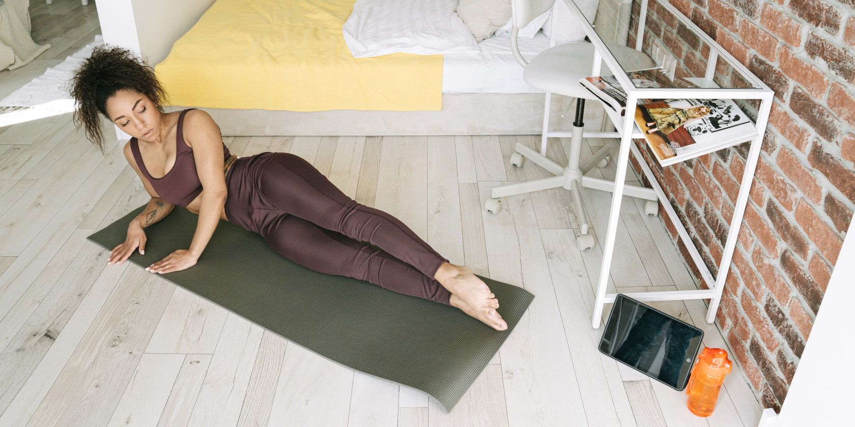 young woman lying on exercise mat in apartment 