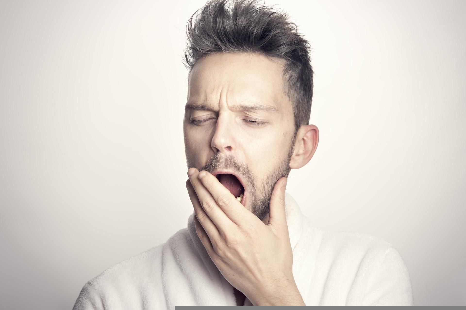 A yawning person covers their mouth