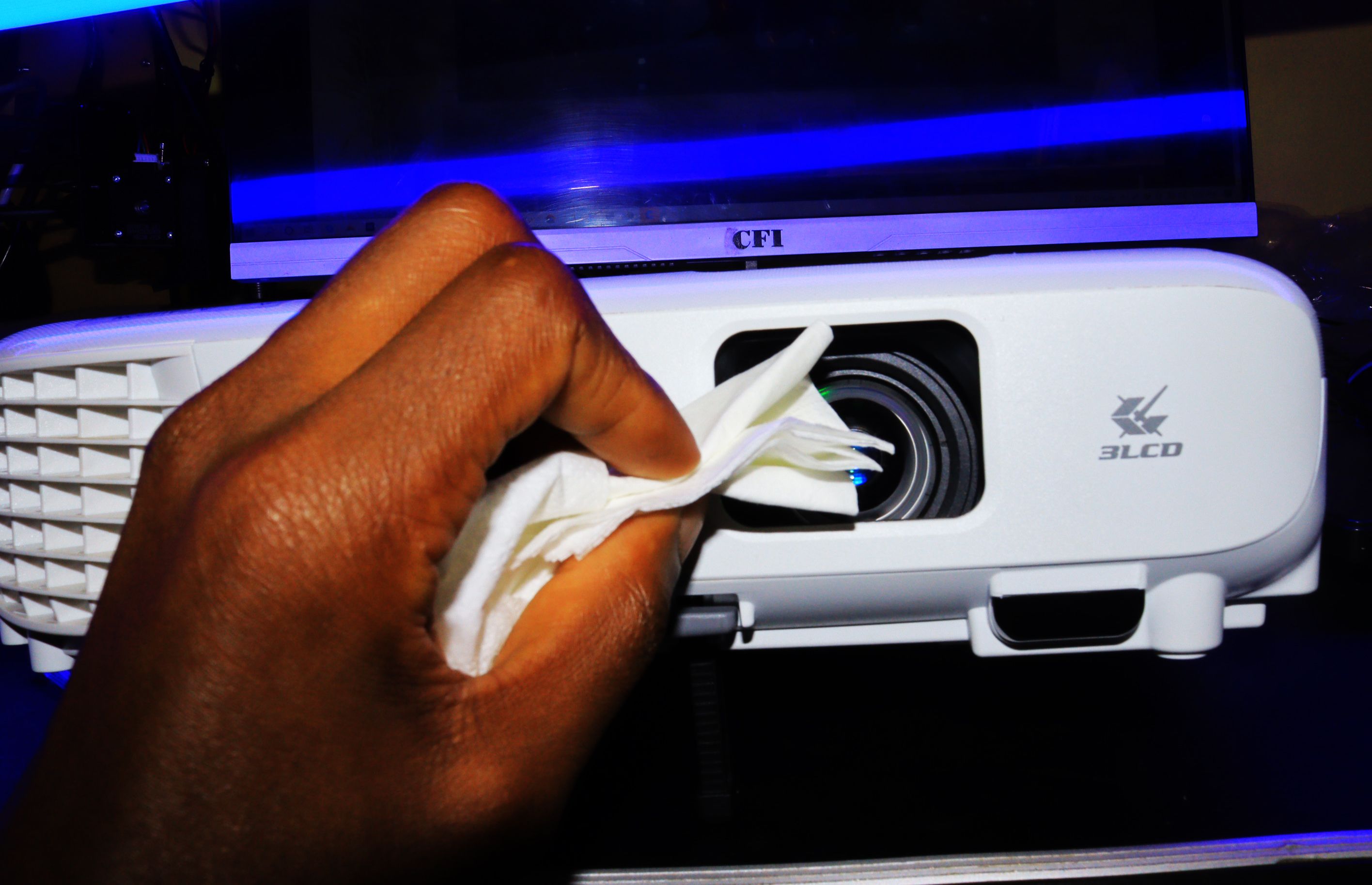 Hand of a black person cleaning-projector-with an Epson projector with a white cloth