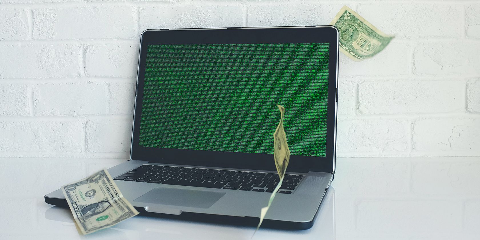 MacBook with dollar notes floating around it.
