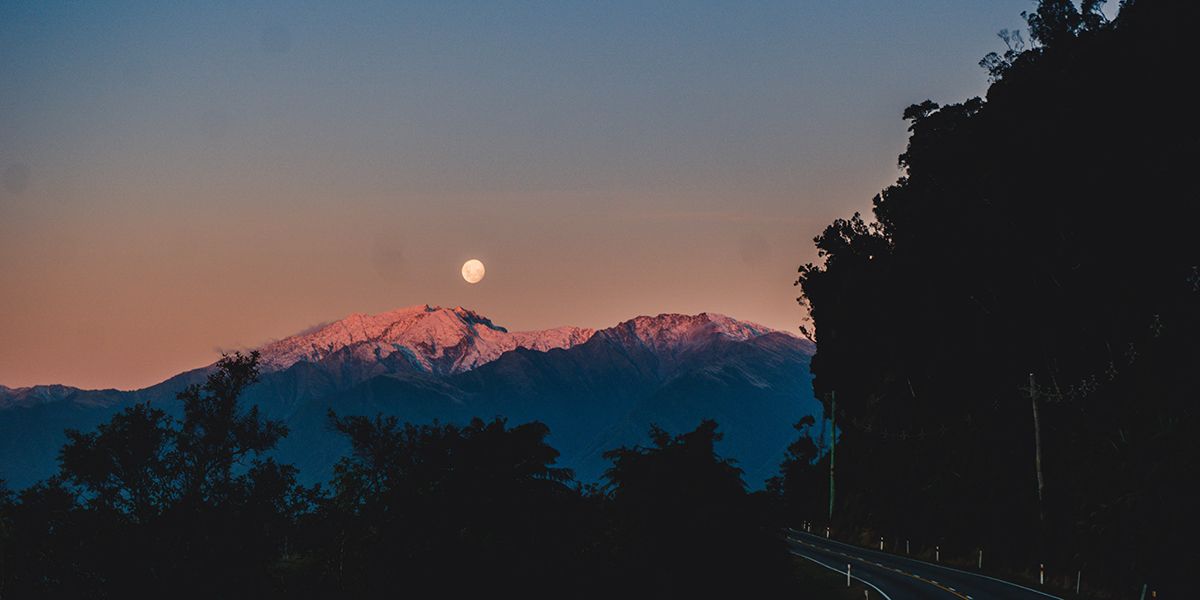 Photo of the moon peeking over the mountains.