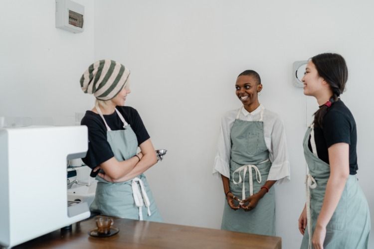 There women standing happily around a coffee machine