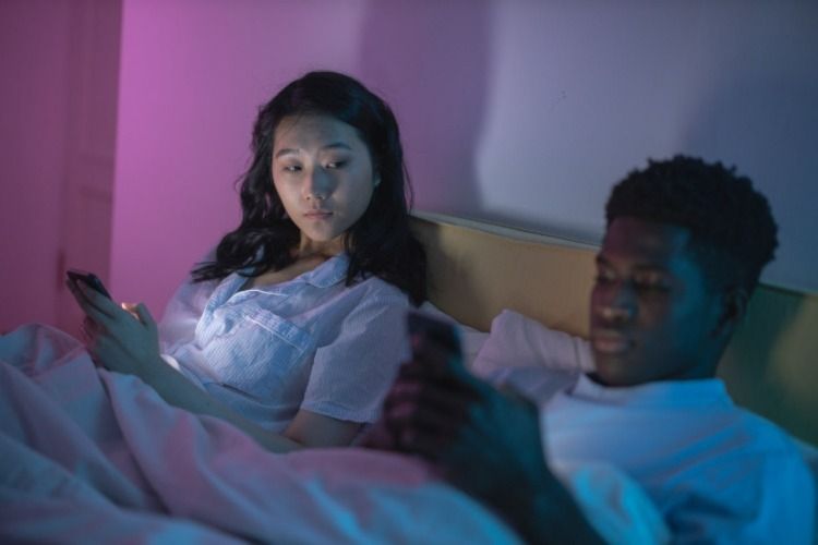 Woman looking at a man scrolling on his phone