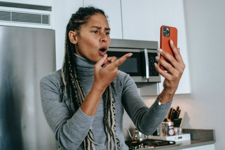 Woman pointing at her phone in shock
