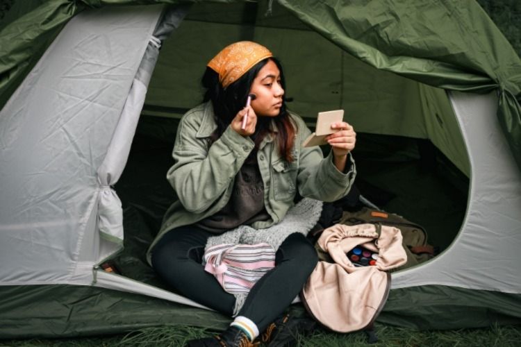 Woman sitting in a tent putting make-up on