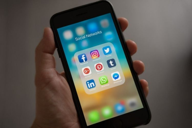 Pessoa segurando o telefone com aplicativos de mídia social como ícones