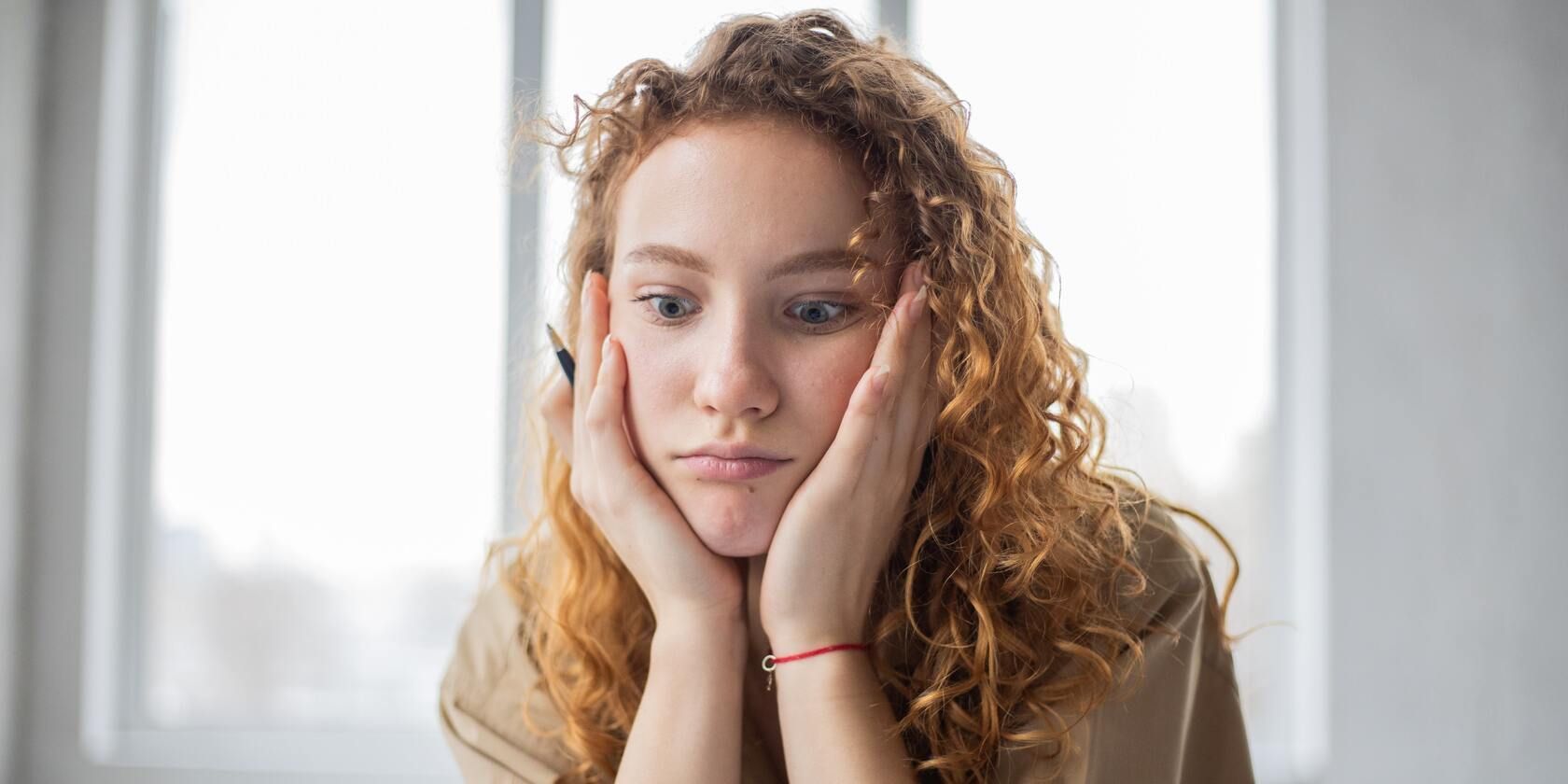 A woman holds her head between her hands and looks bewildered