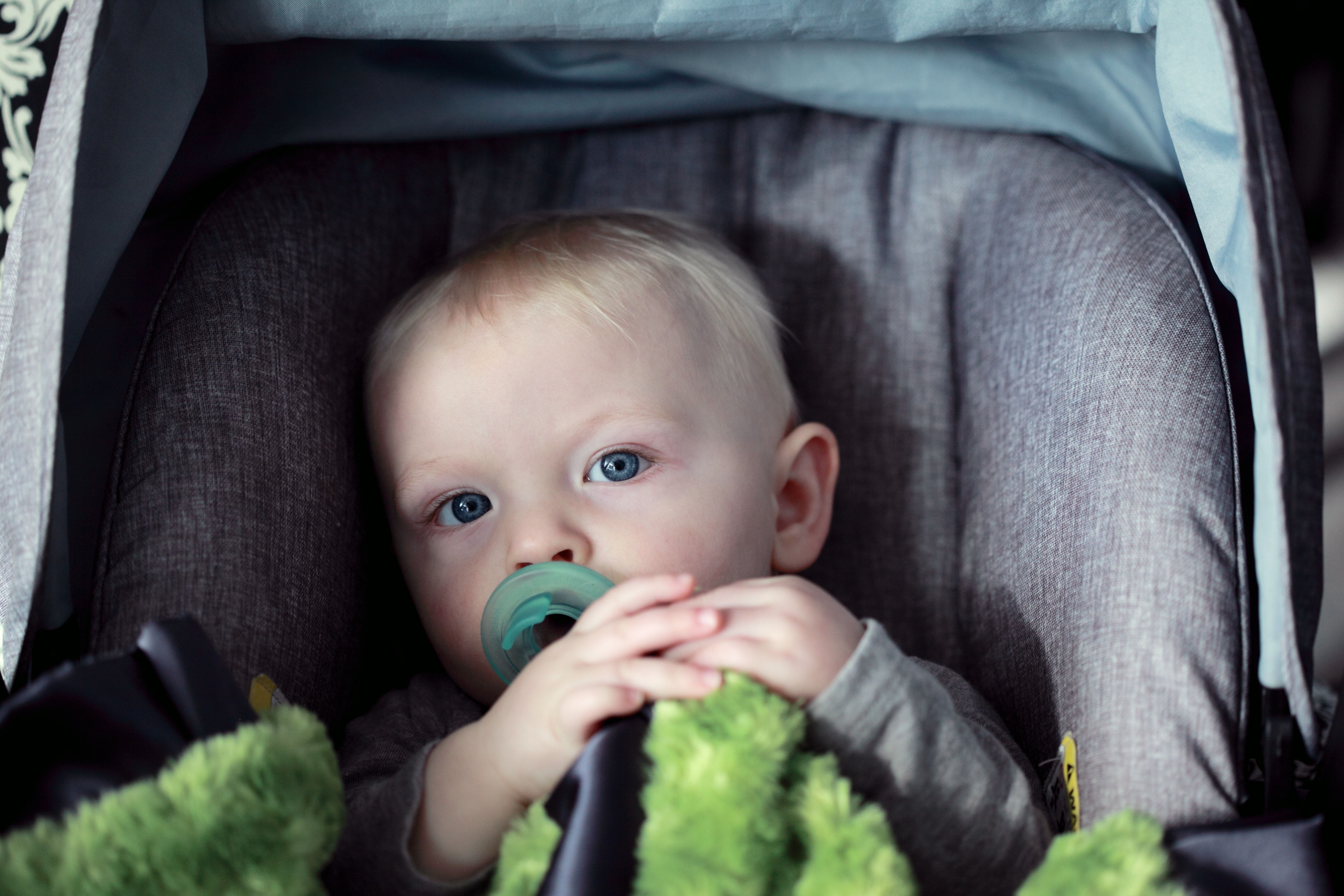 An infant with a pacifier in a car safey seat