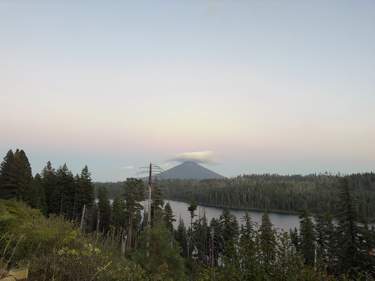 awan lenticular duduk di atas gunung yang jauh saat langit berubah menjadi merah muda saat matahari terbenam iphone photo.