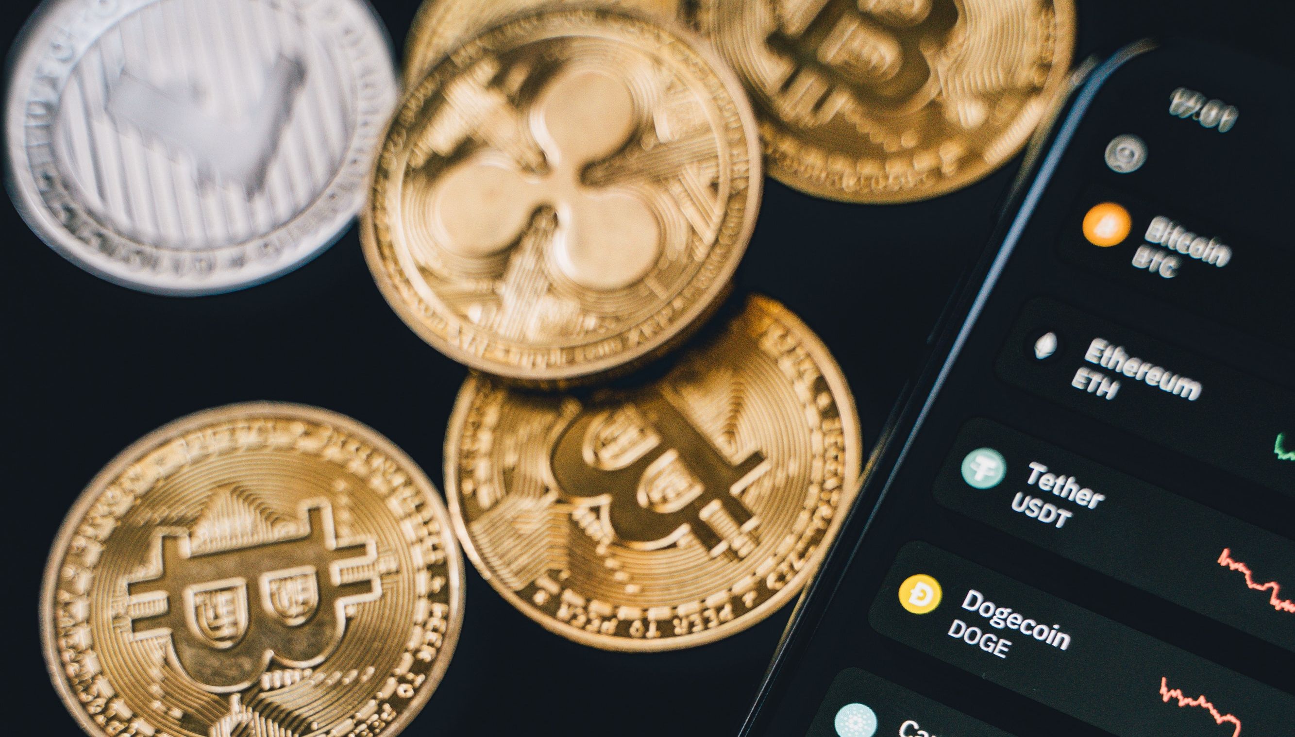 crypto coins next to smartphone displaying crypto statistics