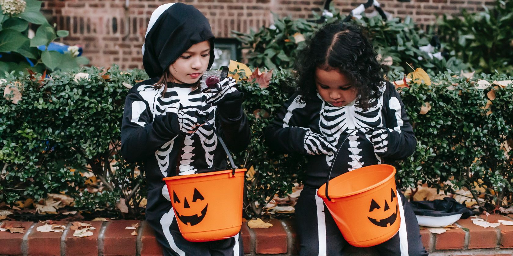 Two children wearing skeleton costumes eating Halloween candy