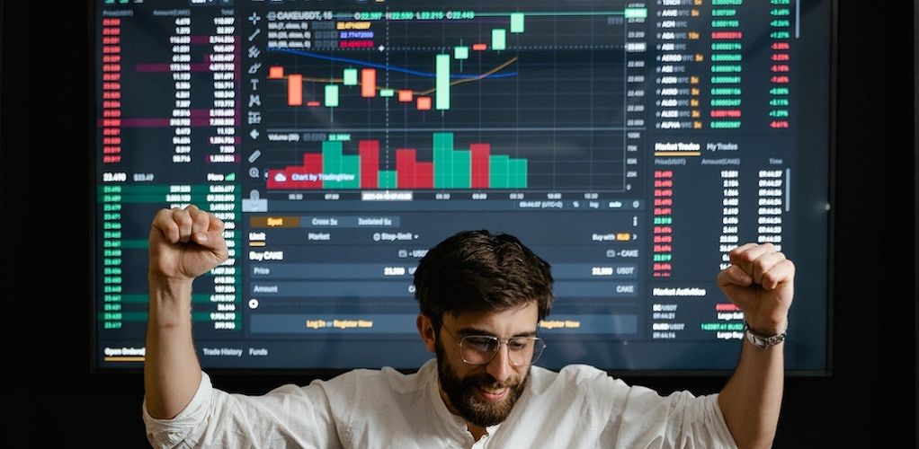 a picture of a man celebrating in front of trading chart