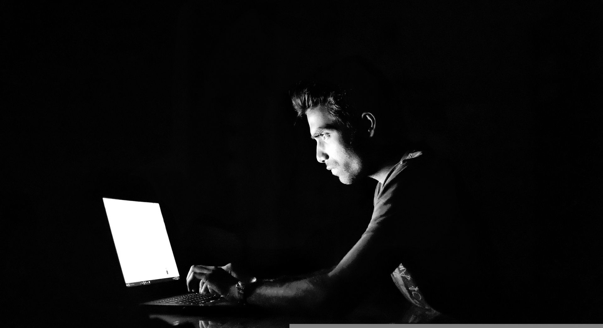 man on laptop in dark room