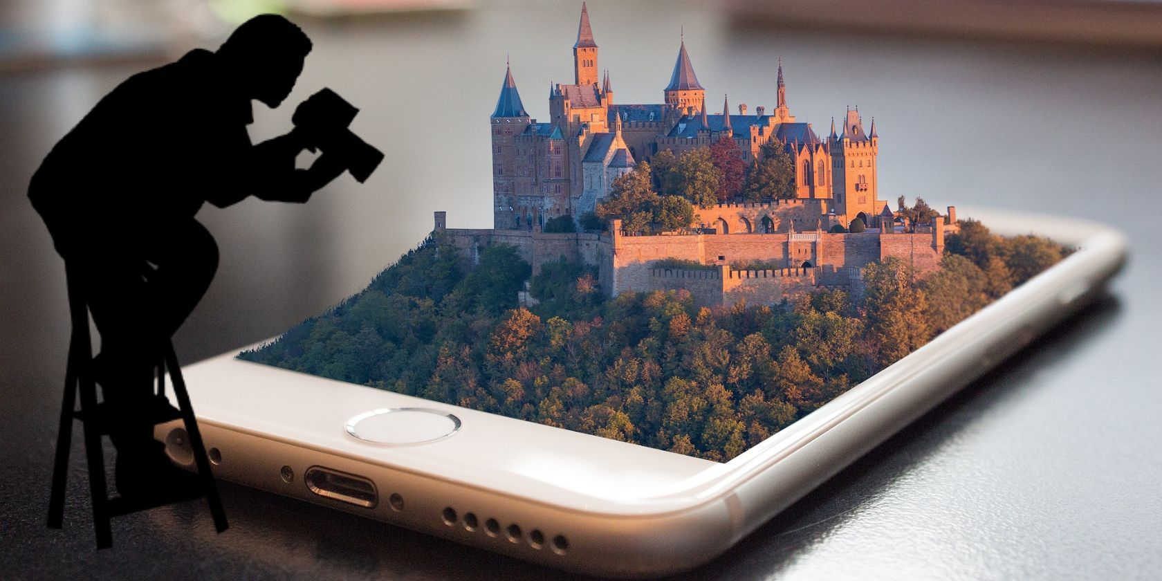 Smartphone with a 3d image of a castle seen on a desk with cameraman standing above