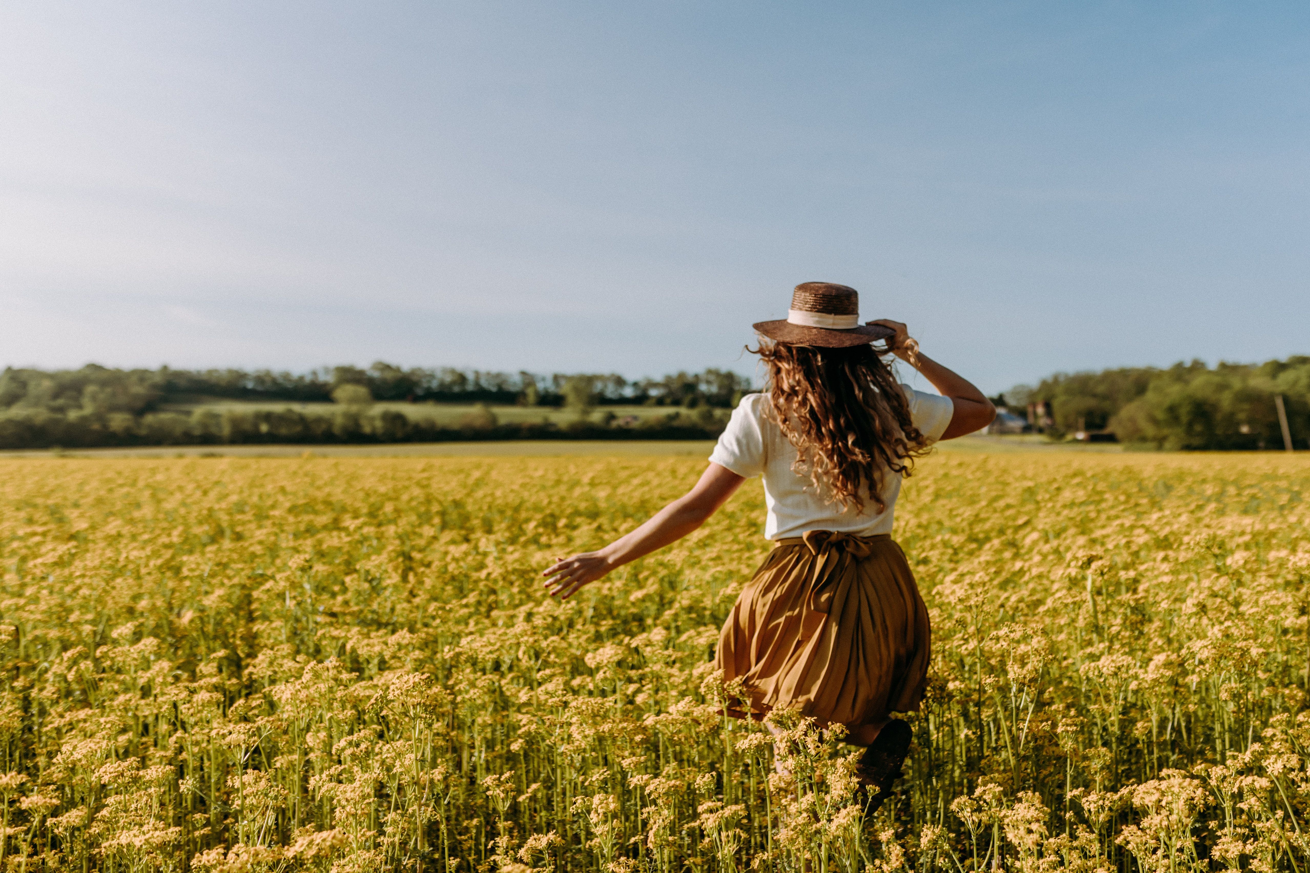 Woman Running Through Flower Field on Sunny Day