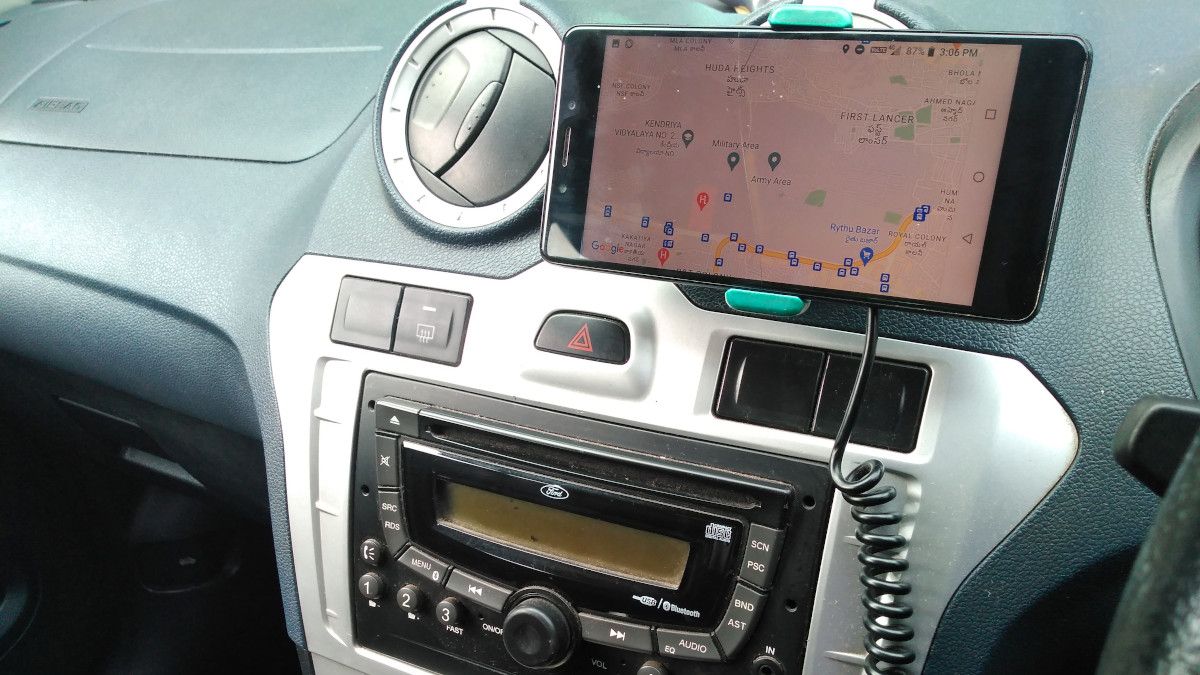 Téléphone affichant Google Maps, fixé au tableau de bord d'une voiture et alimenté par un câble USB