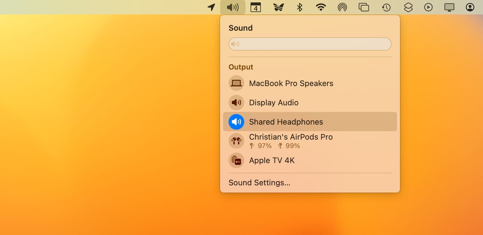 O menu de volume na barra de menus do macOS, com a saída de áudio padrão definida para dois conjuntos de fones de ouvido compartilhados