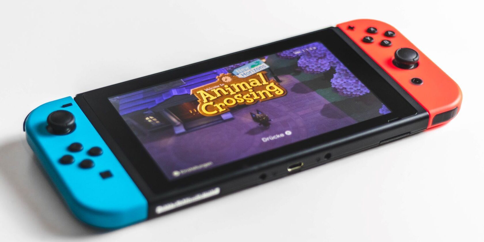 A photo of a Nintendo Switch with red and blue Joy Cons with Animal Crossing running