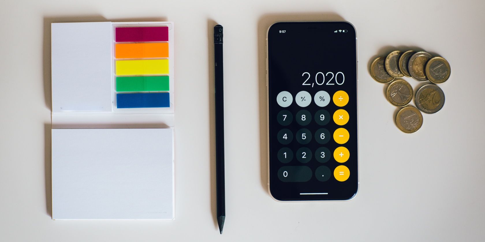 Flatlay of sticky notes, pencil, coins and calculator app on mobile phone
