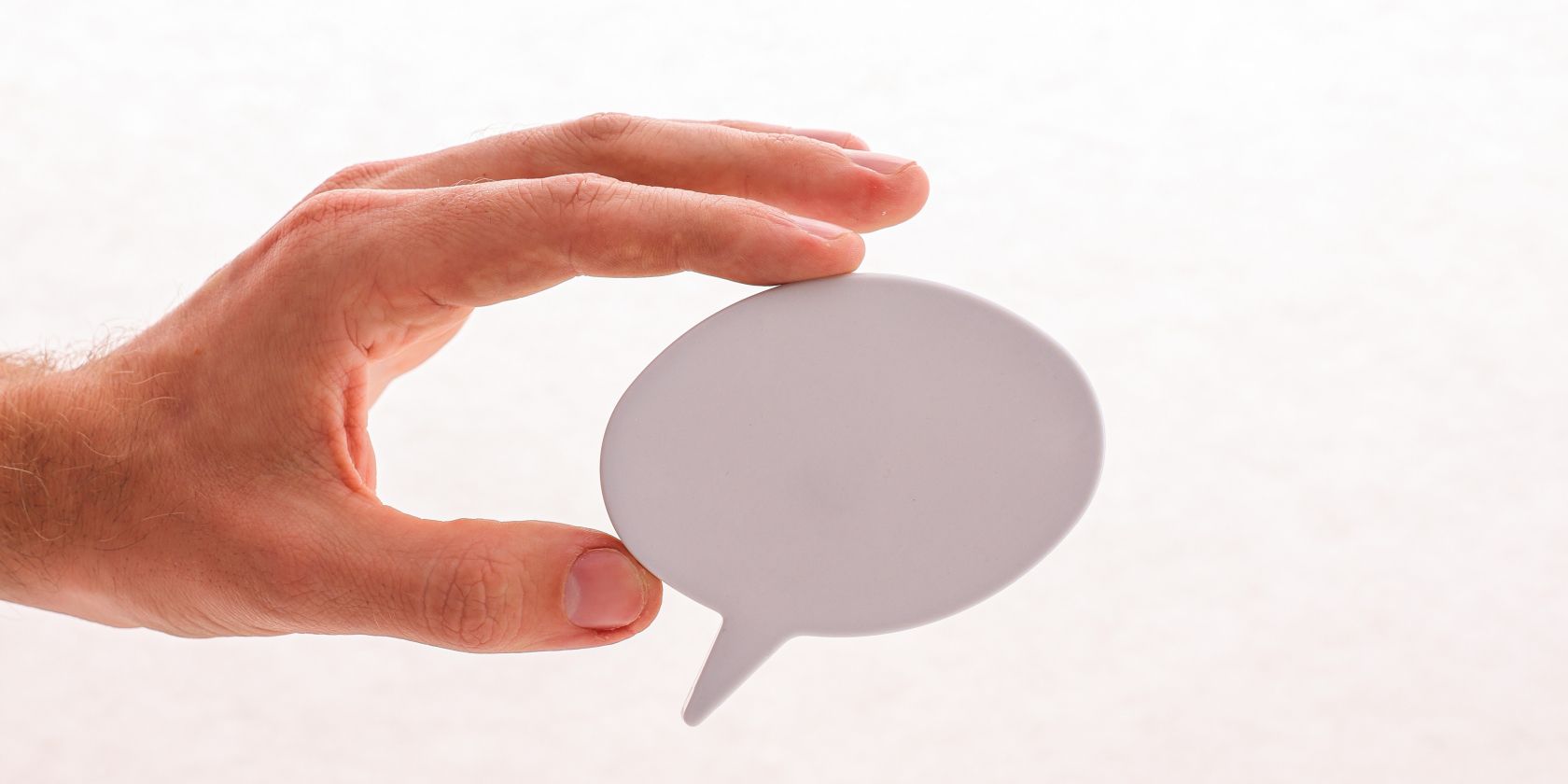A hand holding a paper cutout of a speech bubble
