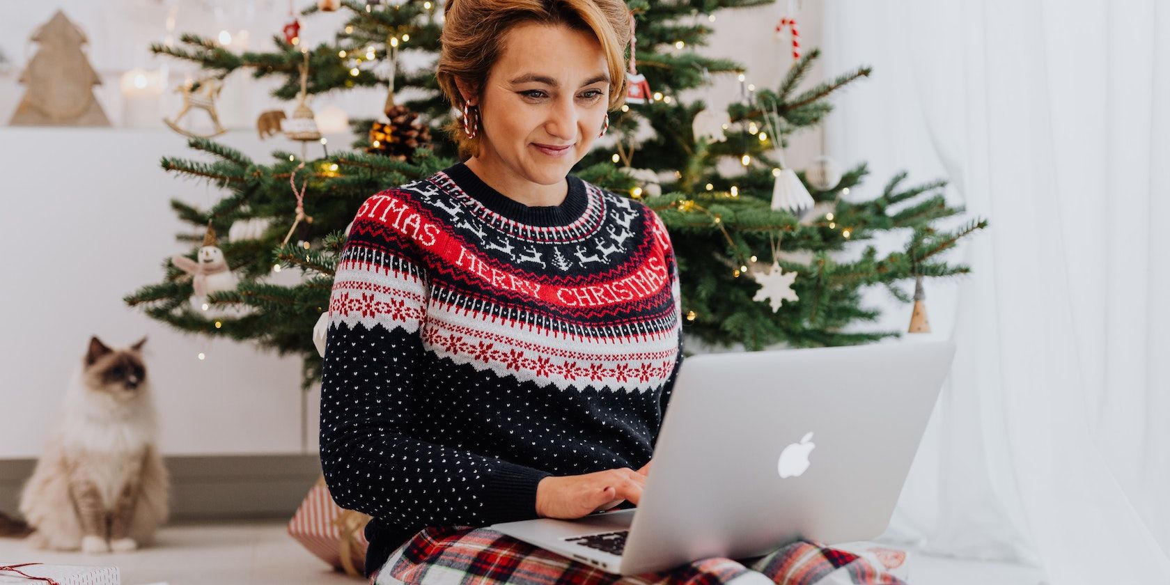 Smiling Woman Using Laptop by Christmas Tree