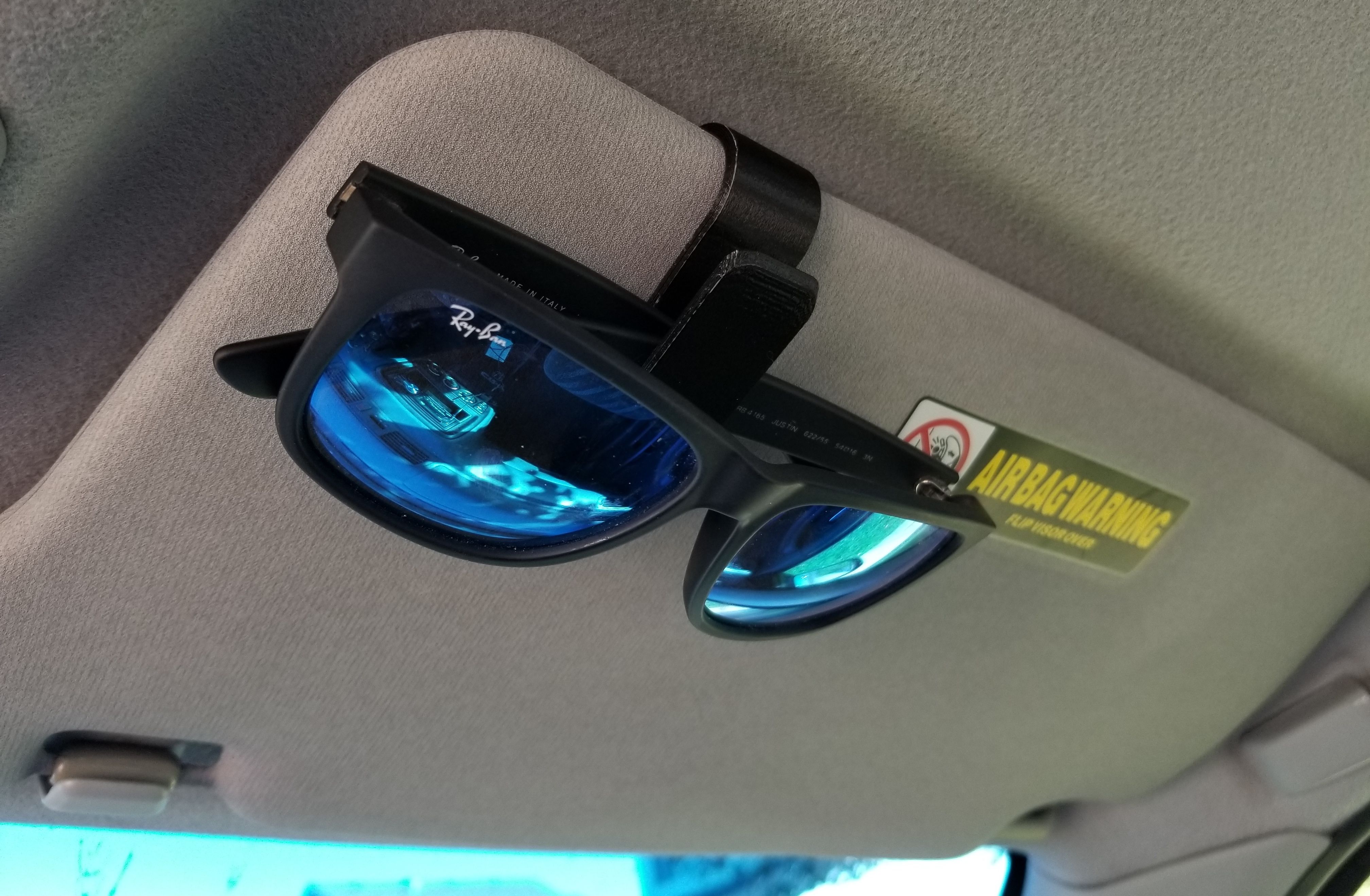 Kacamata hitam dijepitkan ke pelindung di dalam mobil