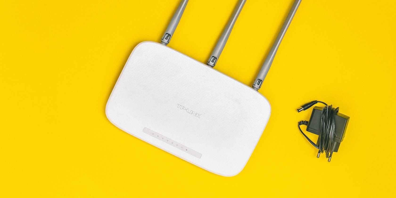 Router Wi-Fi dan charger pada backgrounhd kuning