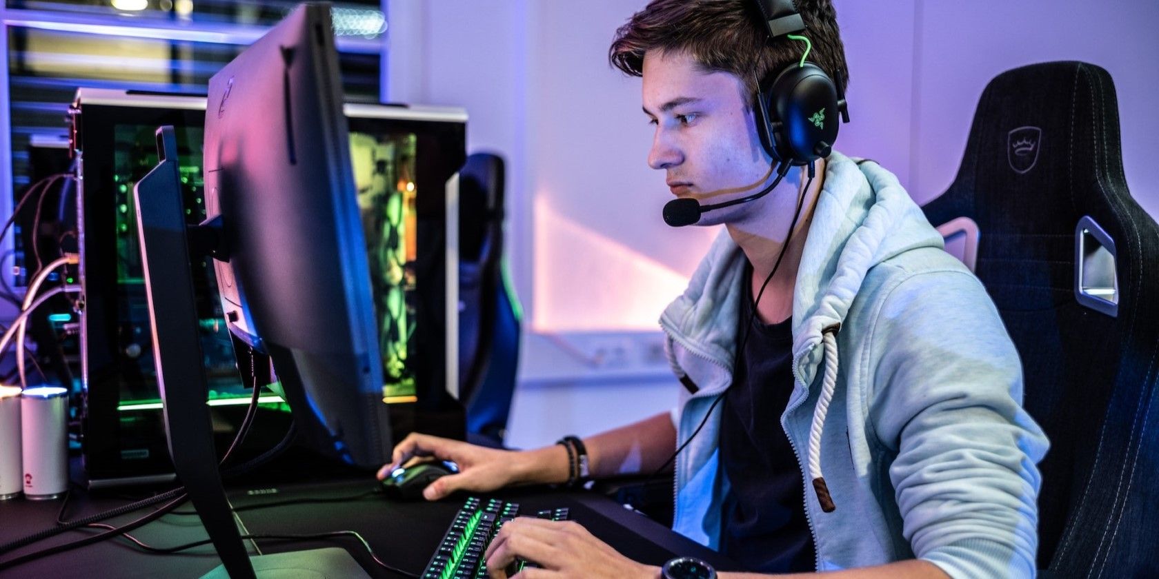 Seorang pria memakai headphone bermain game di komputer