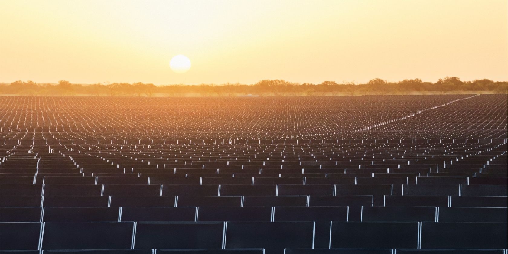 Una granja de energía limpia en el condado de Brown, Texas, con instalaciones de paneles solares que se extienden hasta el horizonte, fotografiada al atardecer