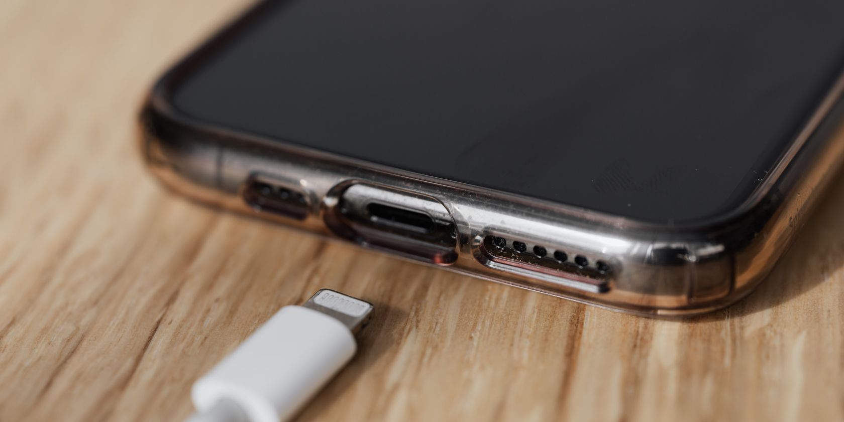 The charging port of an iPhone together with a charger on the table