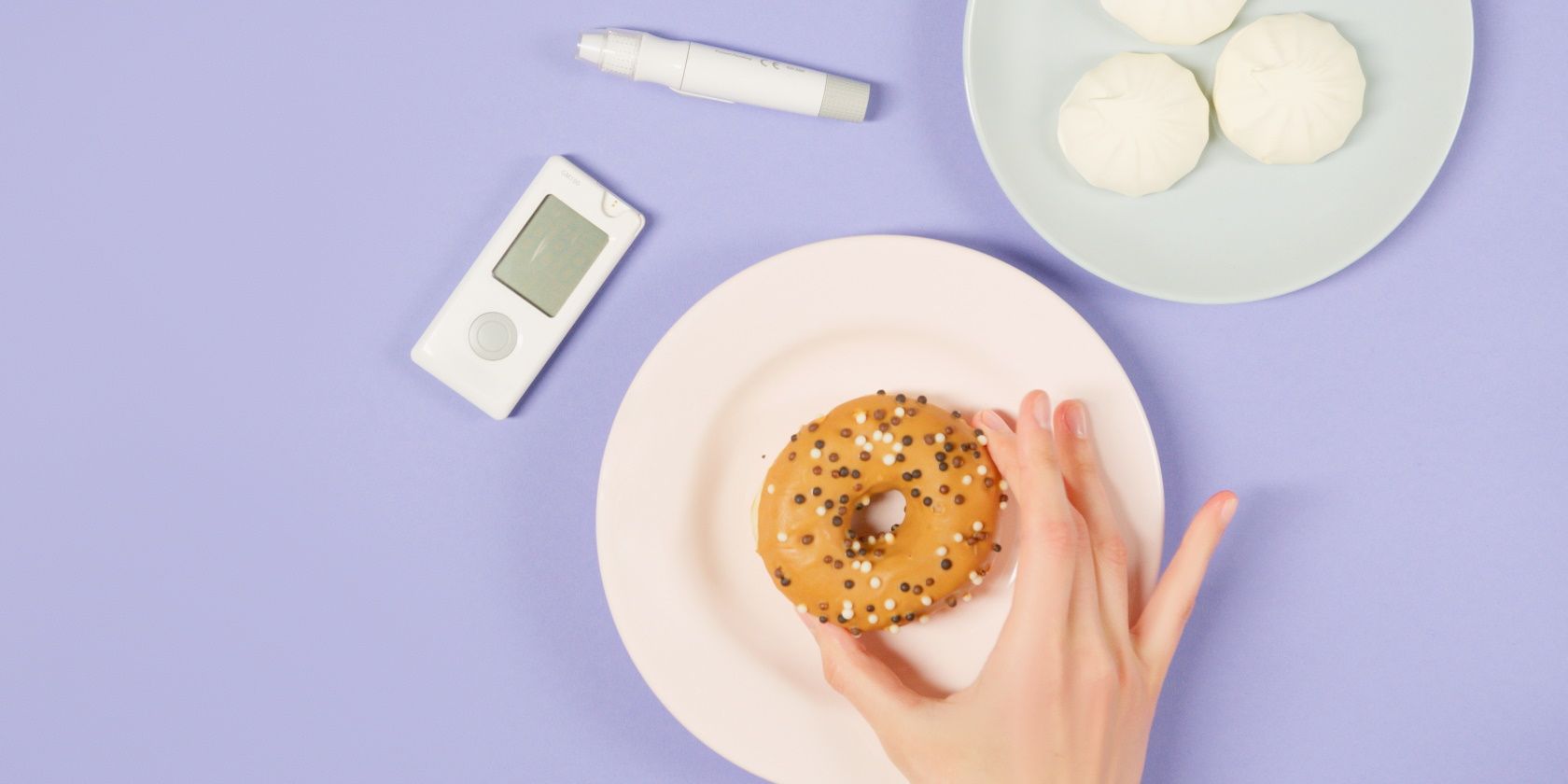 Glucose monitor, white bread on a plate, and hand holding a donut on a plate