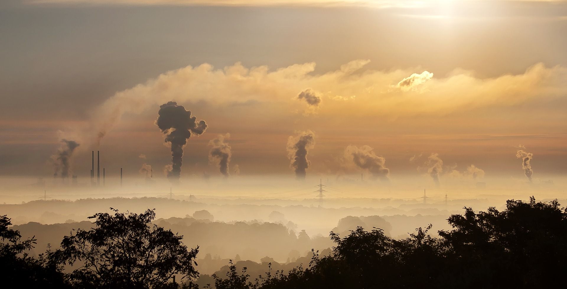 In the horizon, tall smokestacks release industrial pollution and create smog cover