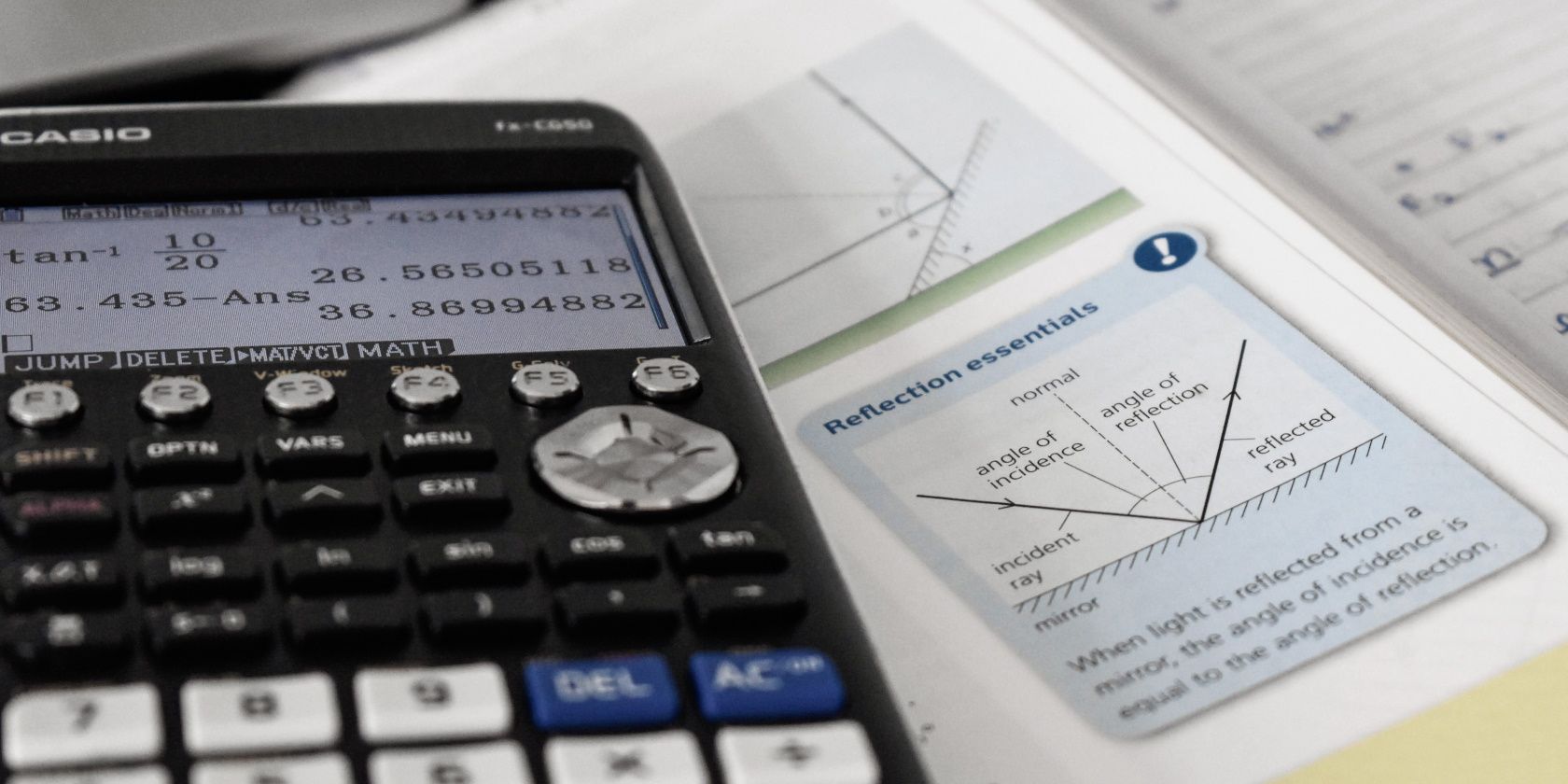 Calculator and paper on desk with math formulas