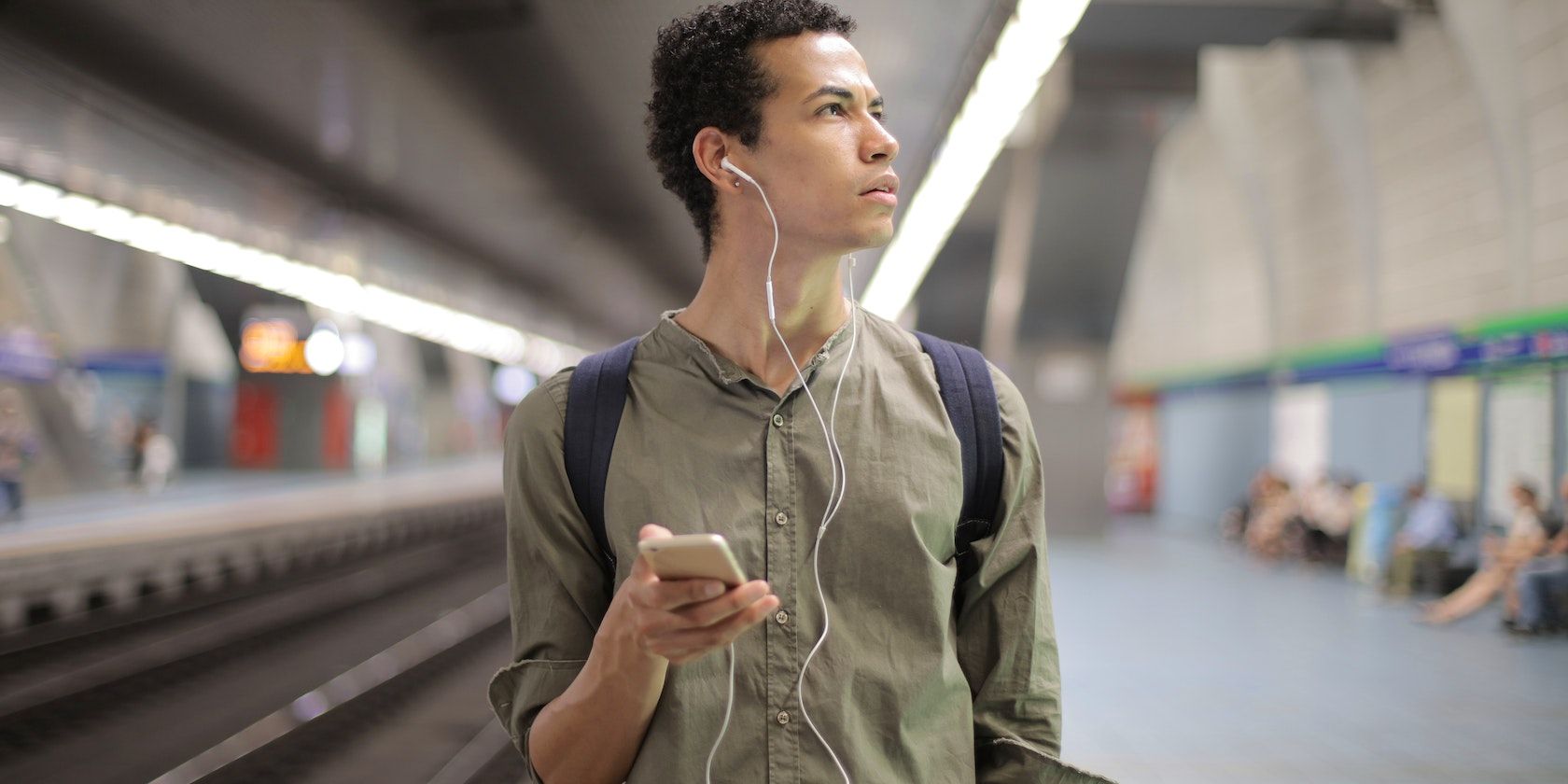 A man listening on headphones in a busy terminal