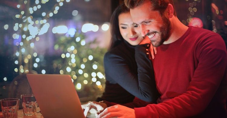 Homem e mulher rindo na frente do laptop
