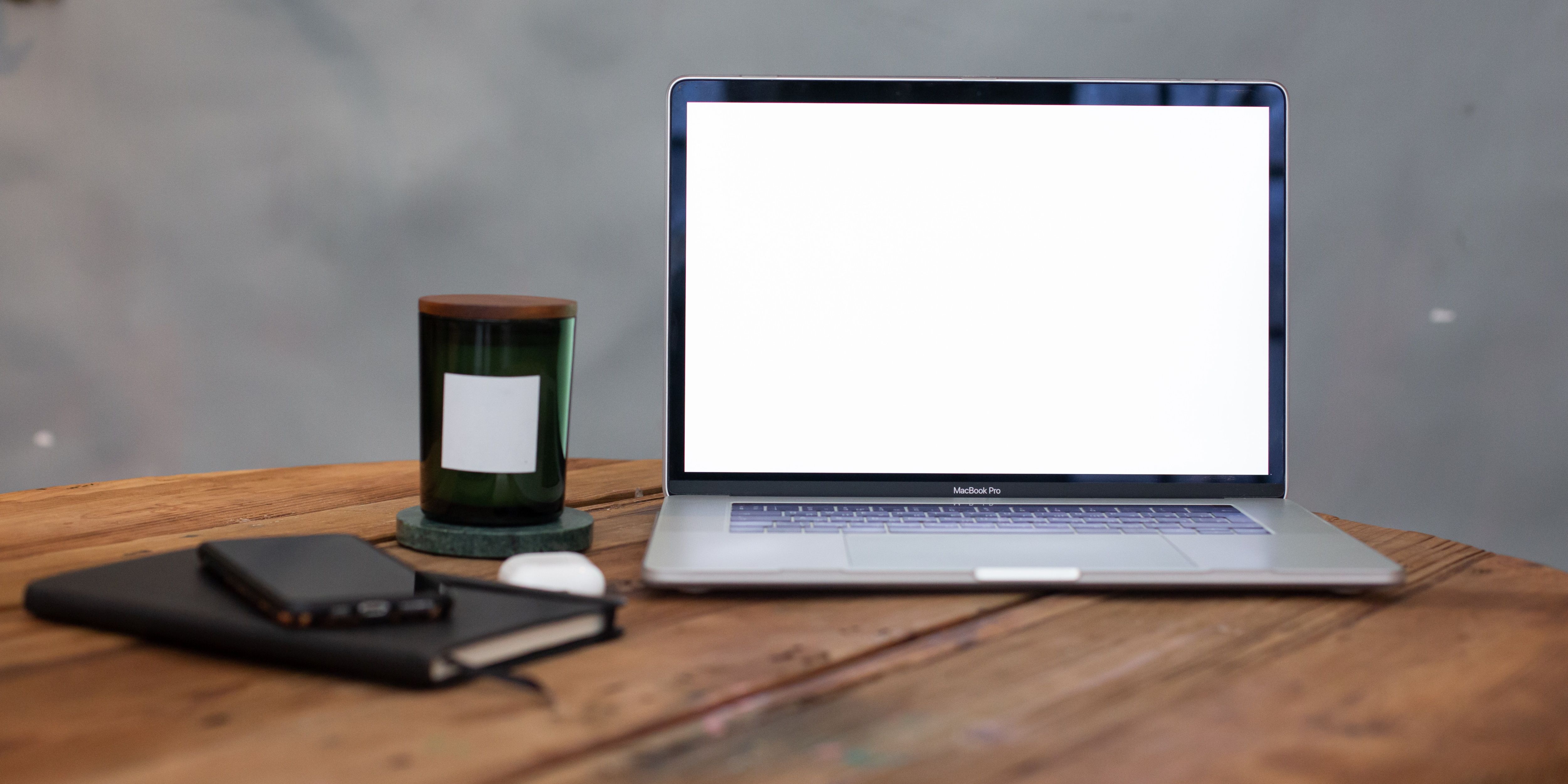 Macbook pro en el escritorio con pantalla en blanco en blanco