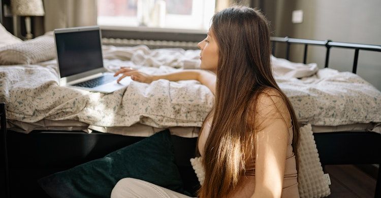 Mulher grávida sentada em seu quarto com um computador