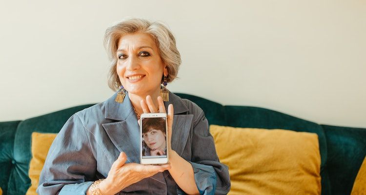 Một người phụ nữ lớn tuổi khoe ảnh của mình trên điện thoại thông minh