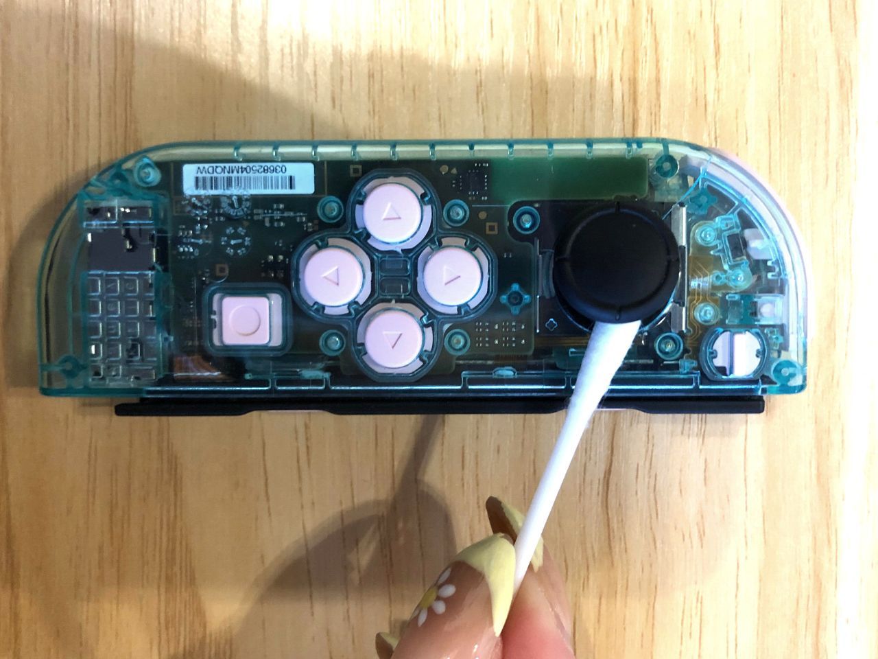 Using a cotton swab to clean under the Joy Con analog stick