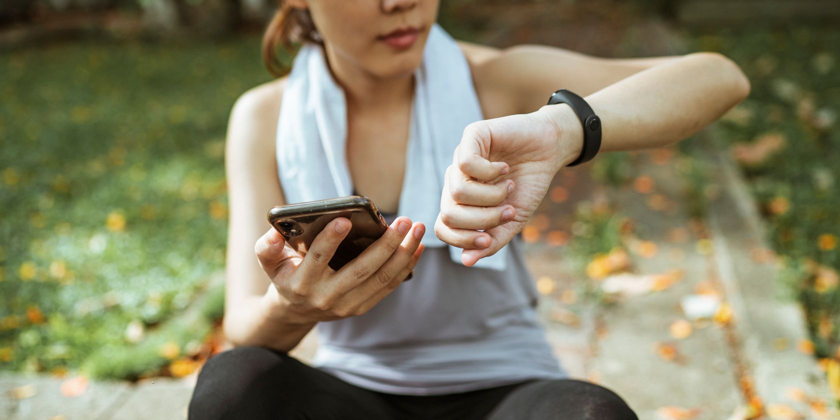 woman checking her fitness tracker and phone while exercising