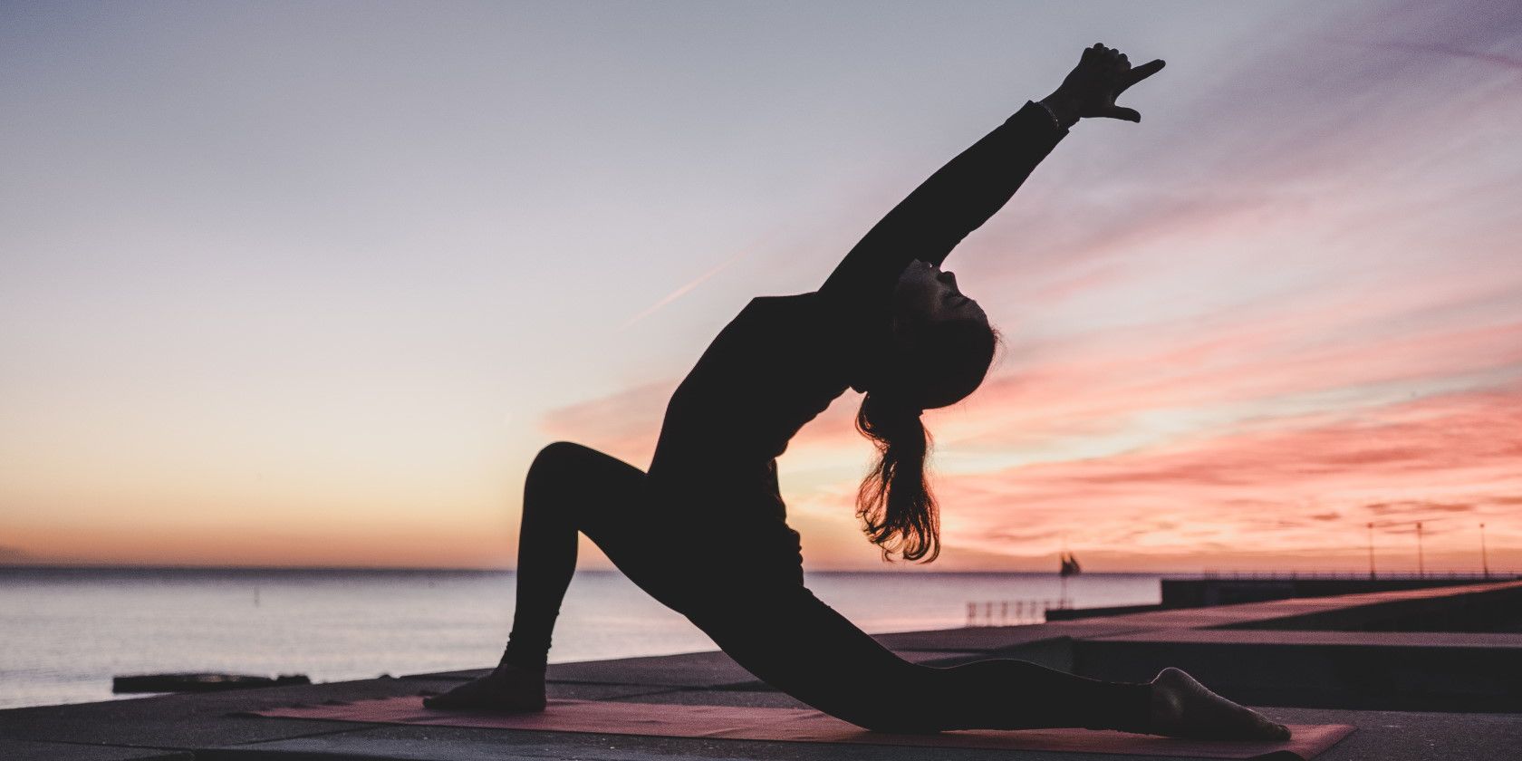 silhouette of woman practicing yoga outdoors at sunset