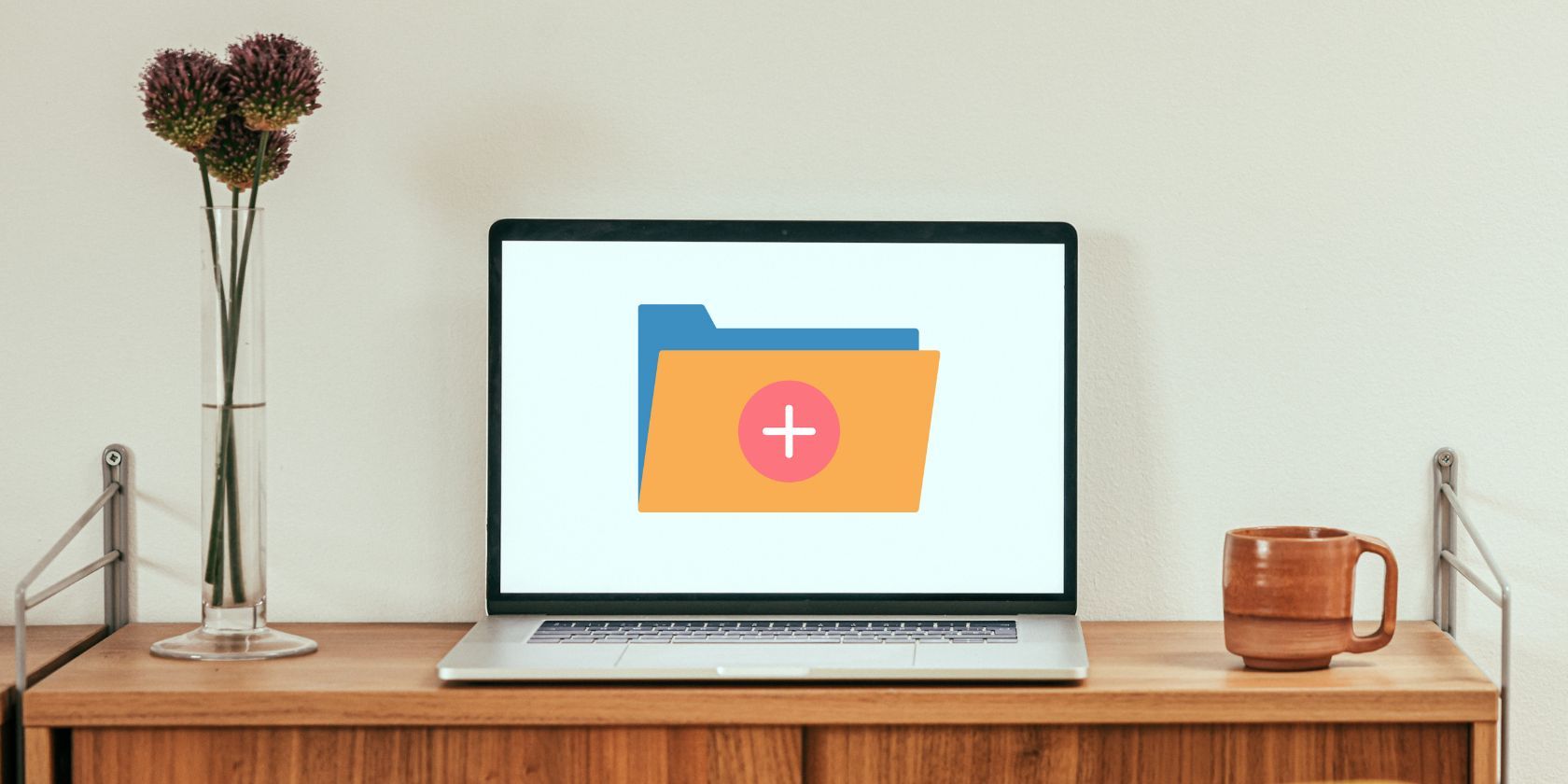 A Laptop With a New Folder Icon on a Wooden Table Near White Wall