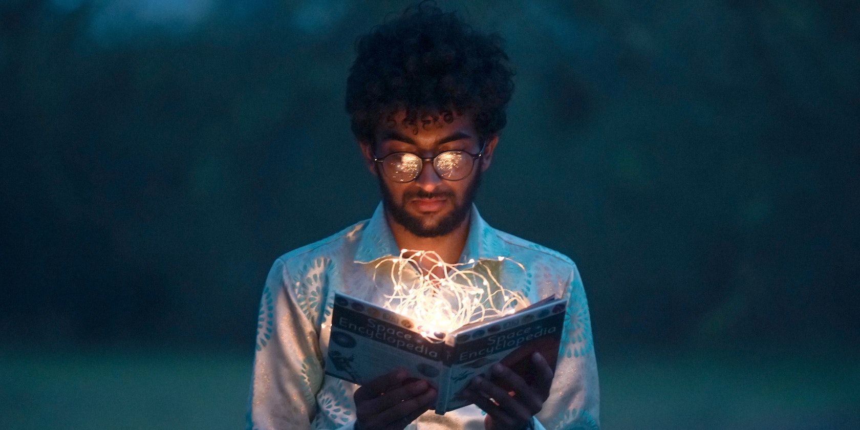 A man holding a book is emitting light