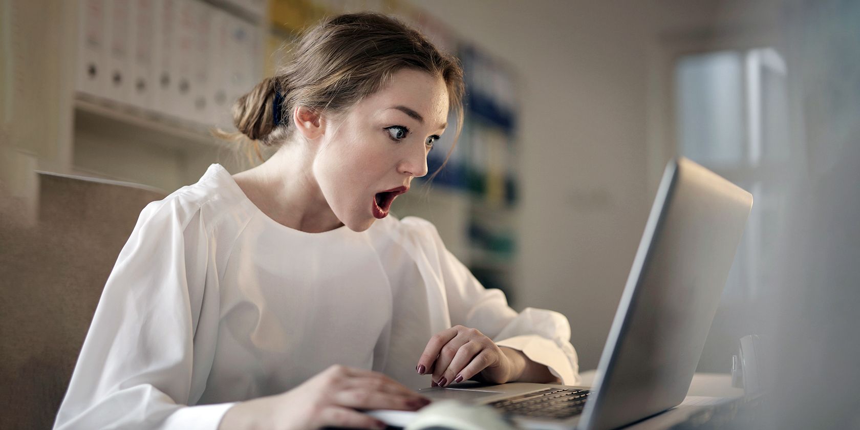 Une femme étonnée par ce qui s'affiche sur l'écran de son ordinateur.