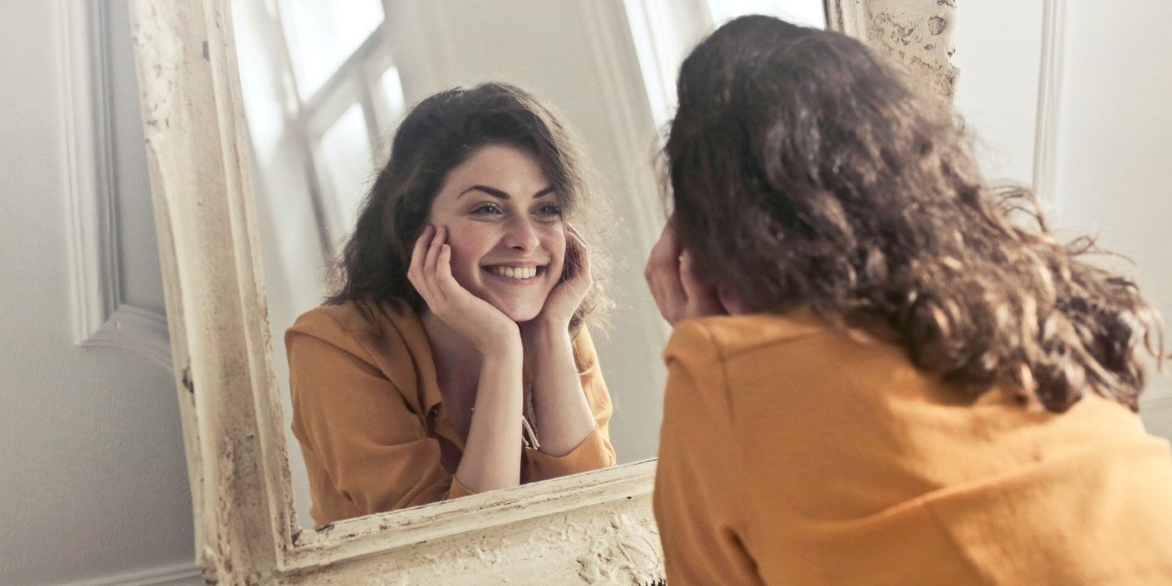 woman smiling at herself in mirror