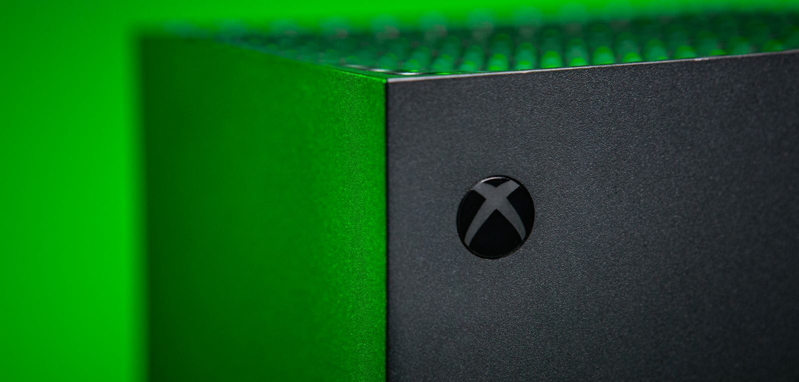 A photo of the power button on an Xbox Series X with a green background