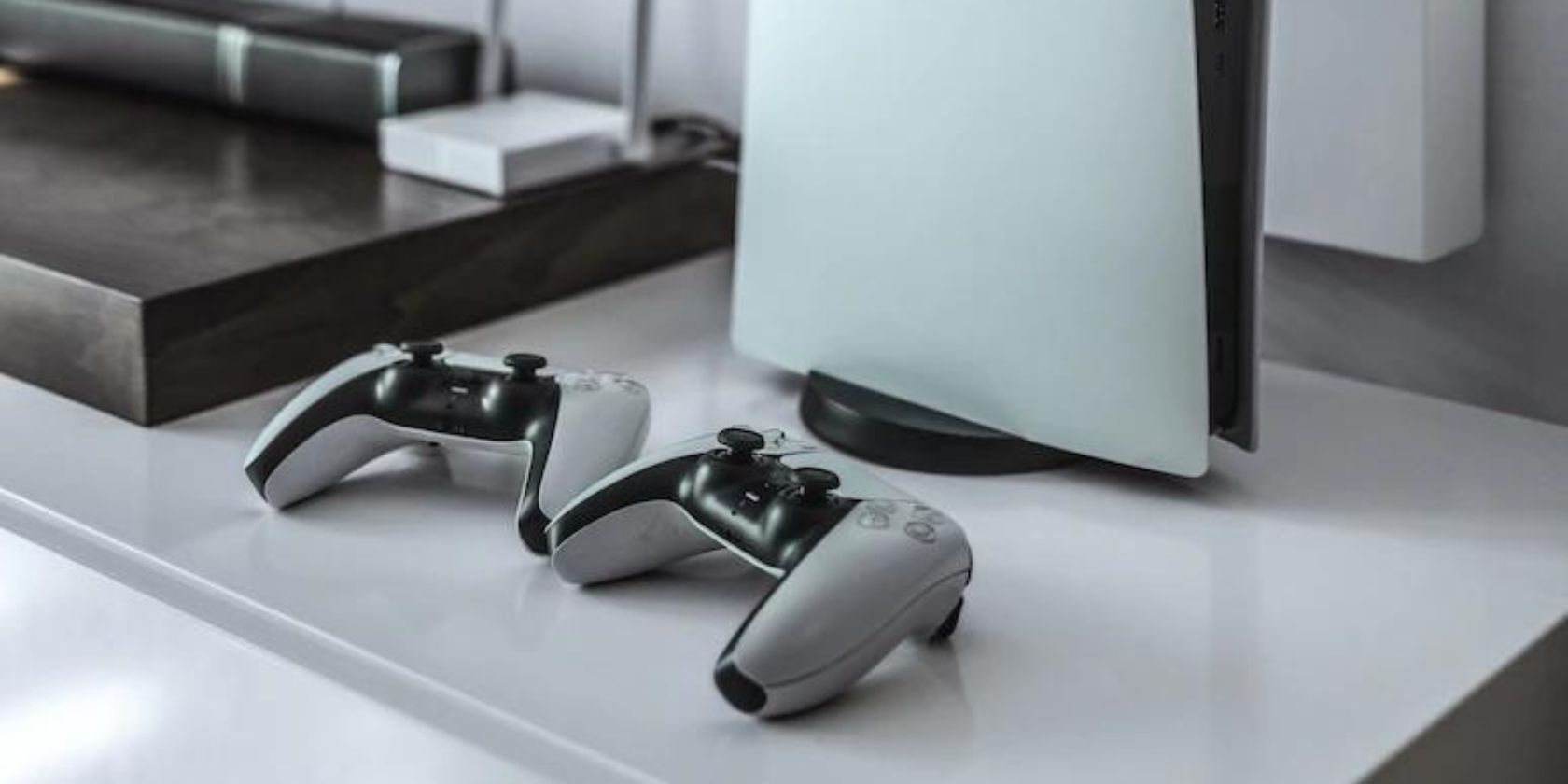 Black and white photo of two DualSense controllers next to a PlayStation 5