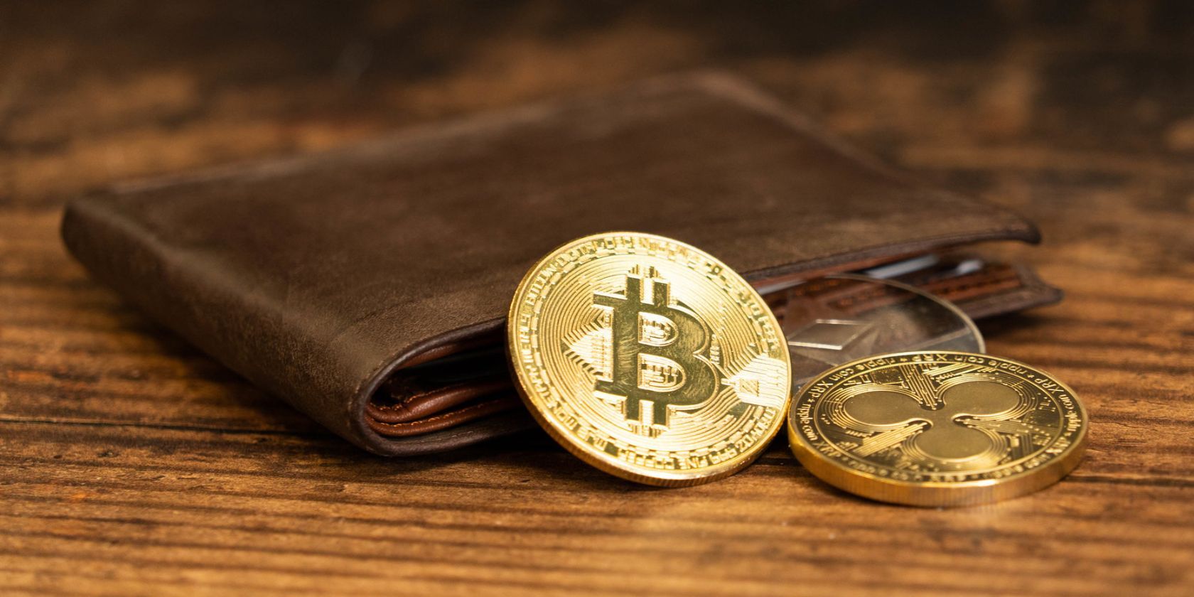 bitcoin and xrp coins next to brown leather wallet