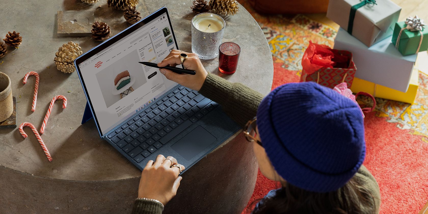 Donna shopping online con laptop circondato da decorazioni natalizie